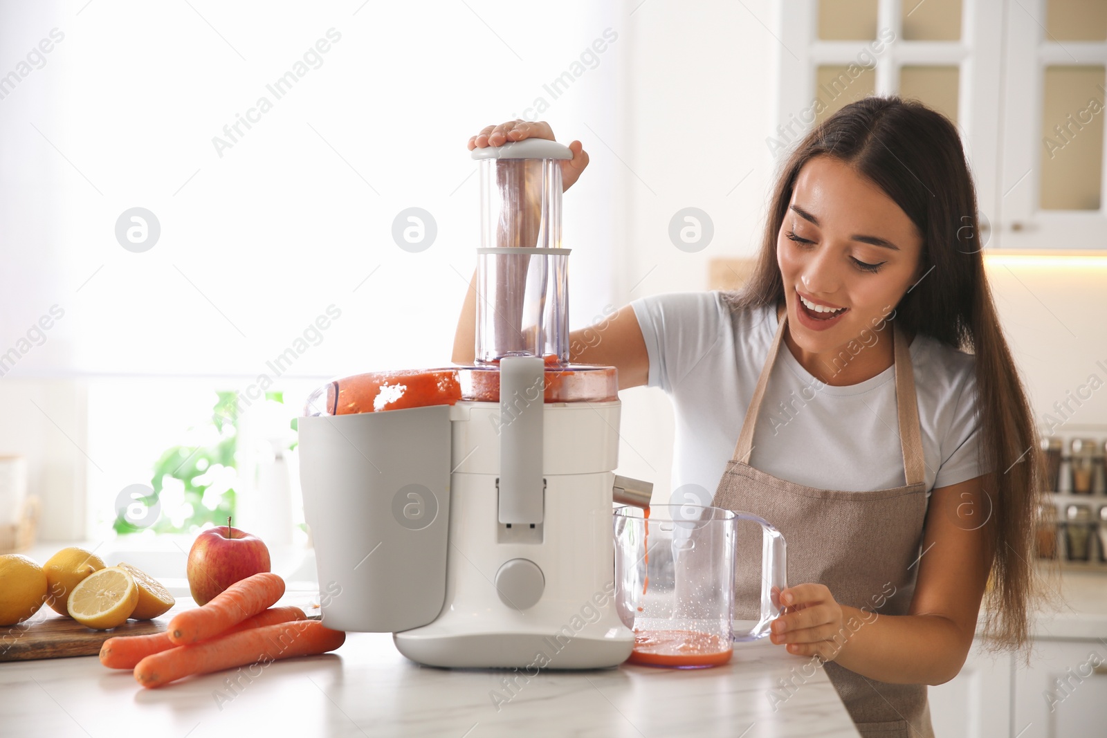 Photo of Young woman making tasty fresh juice at table in kitchen