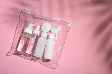 Cosmetic travel kit in plastic bag on pink background, top view and space for text. Bath accessories