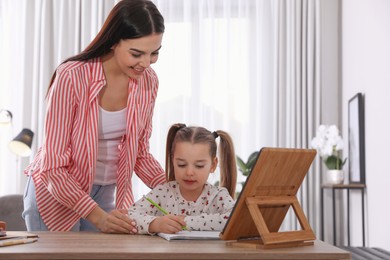 Mother helping her daughter with homework using tablet at home