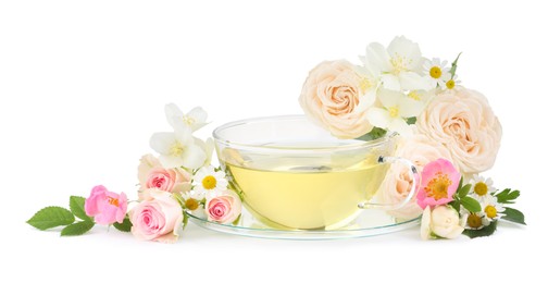 Aromatic herbal tea in glass cup and flowers isolated on white