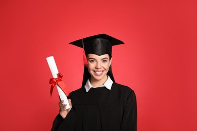 Photo of Happy student with graduation hat and diploma on red background