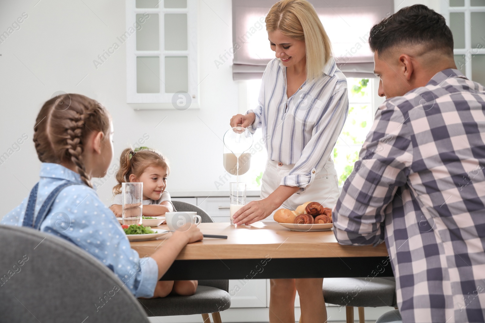 Photo of Happy family having breakfast together at table in modern kitchen