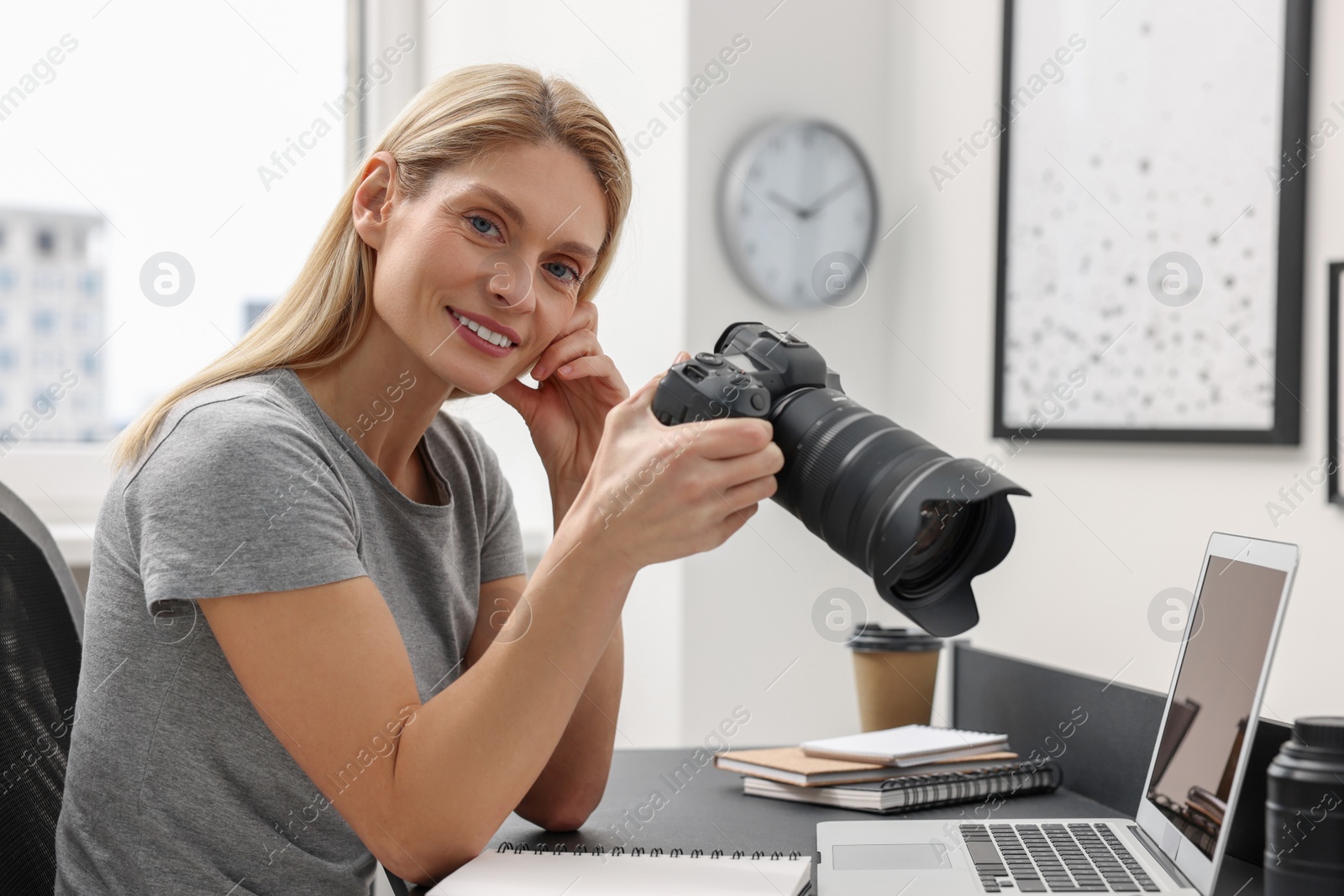 Photo of Professional photographer with digital camera at table in office