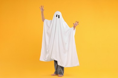 Photo of Woman in white ghost costume on yellow background. Halloween celebration