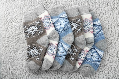 Photo of Knitted socks on grey fur background, flat lay