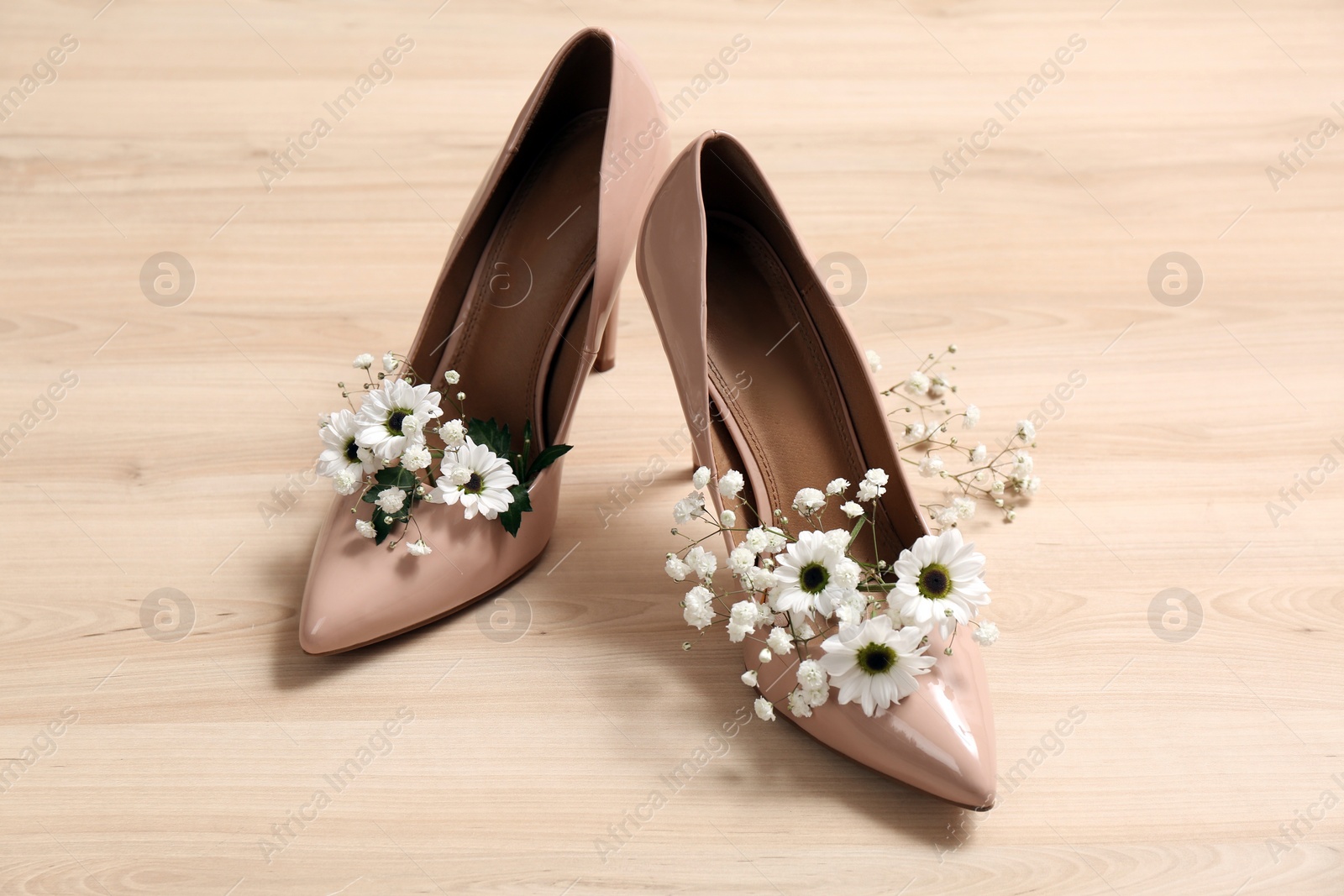 Photo of Women's shoes with beautiful flowers on wooden surface