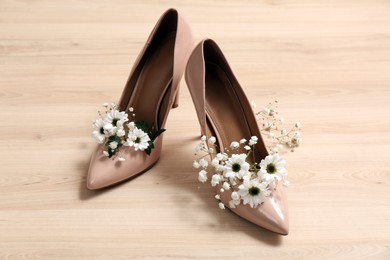 Women's shoes with beautiful flowers on wooden surface