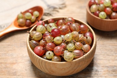 Photo of Bowl of fresh ripe gooseberries on wooden table, closeup