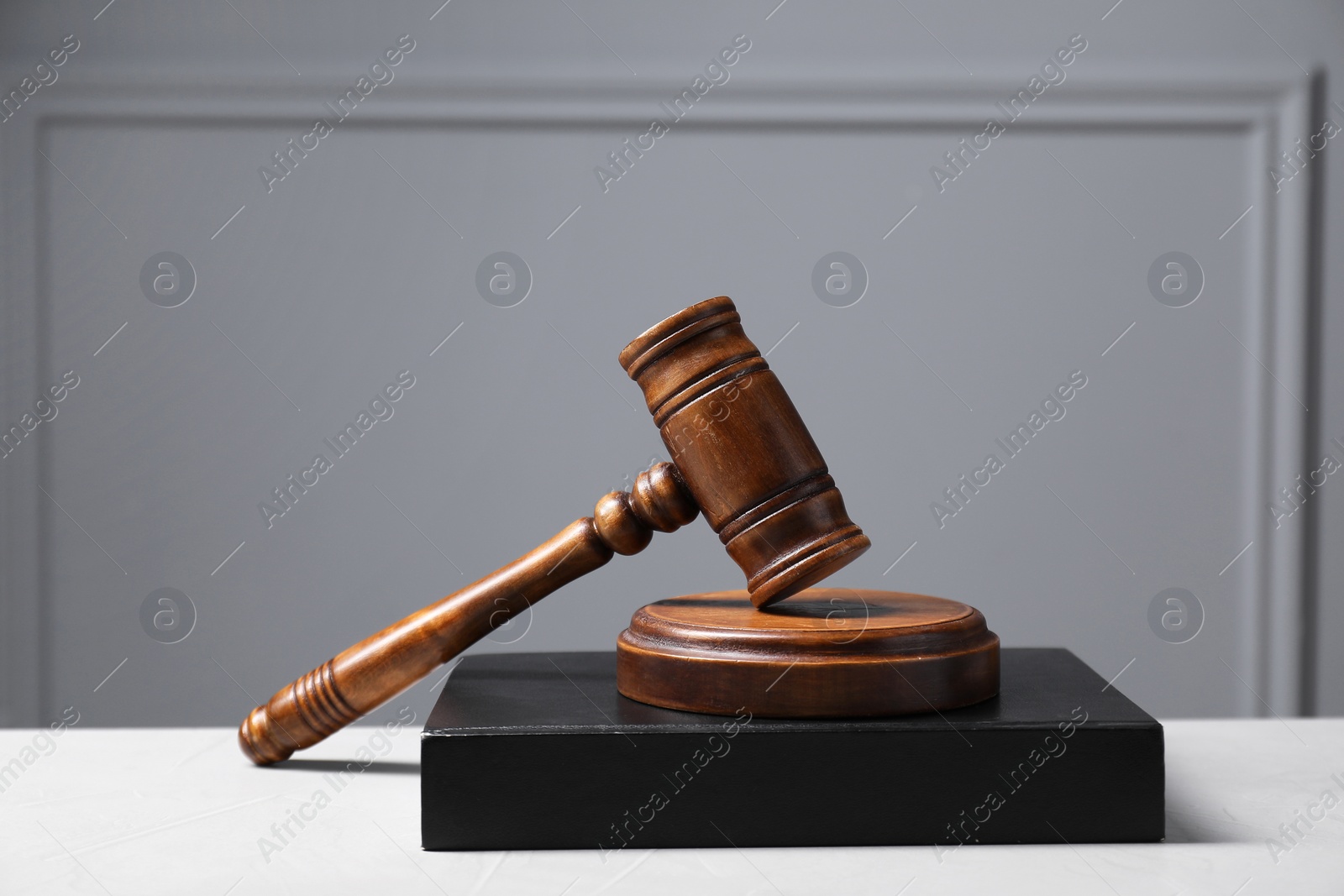 Photo of Law. Book, gavel and sound block on light table against gray background