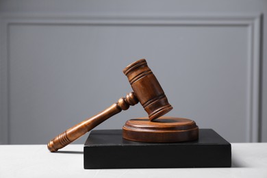 Photo of Law. Book, gavel and sound block on light table against gray background