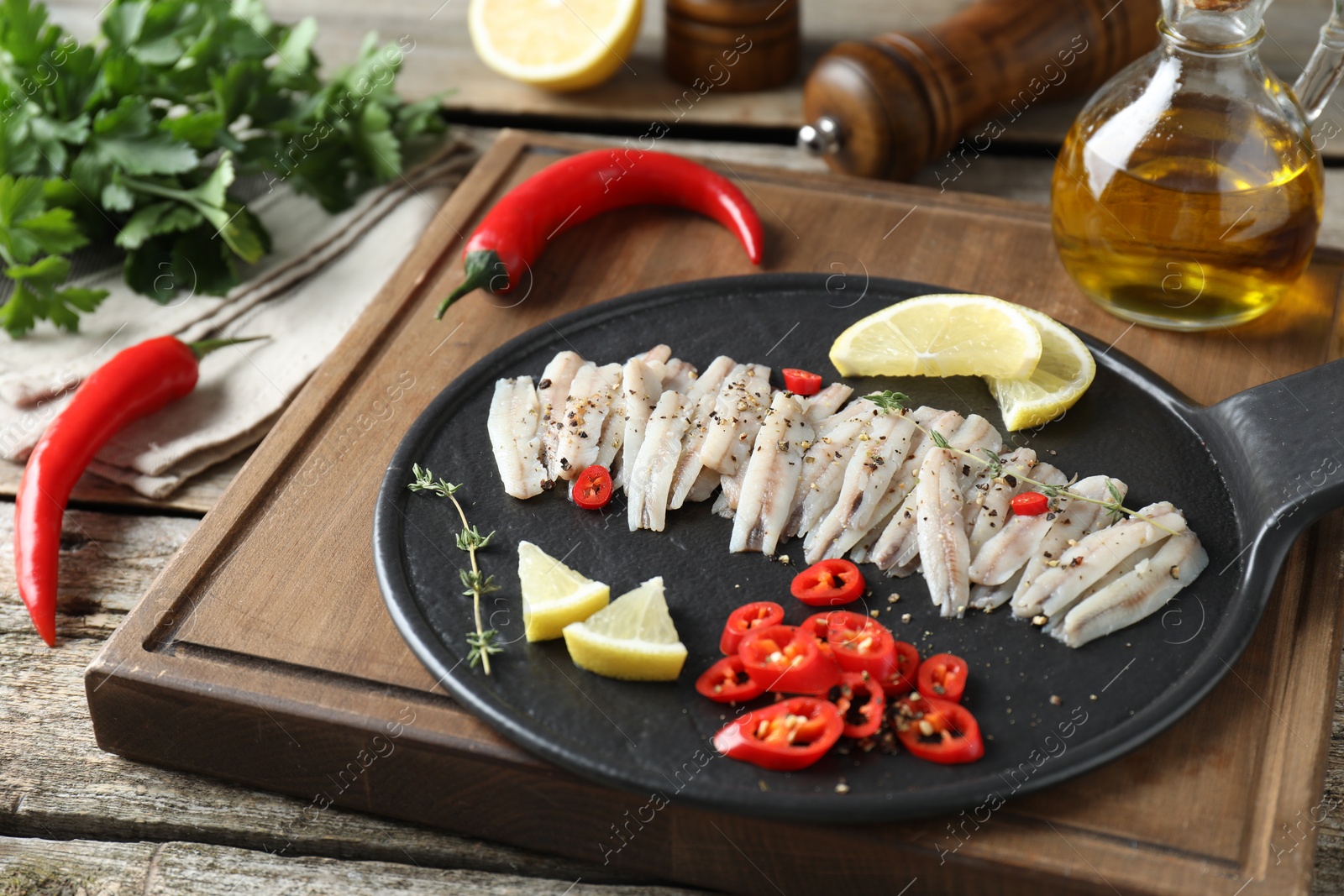 Photo of Tasty anchovies with spices and lemon slices on table