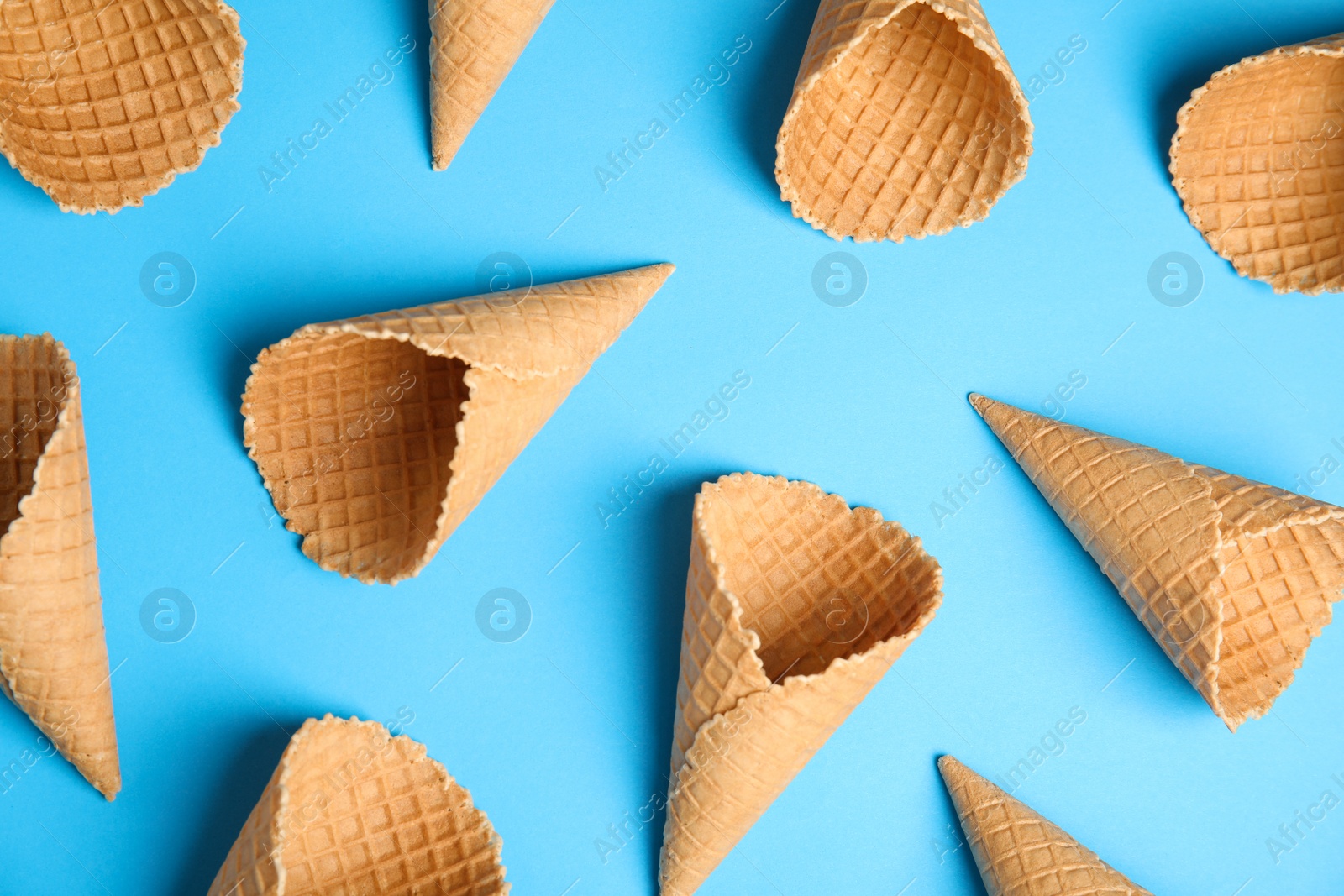 Photo of Waffle empty ice cream cones on color background, flat lay