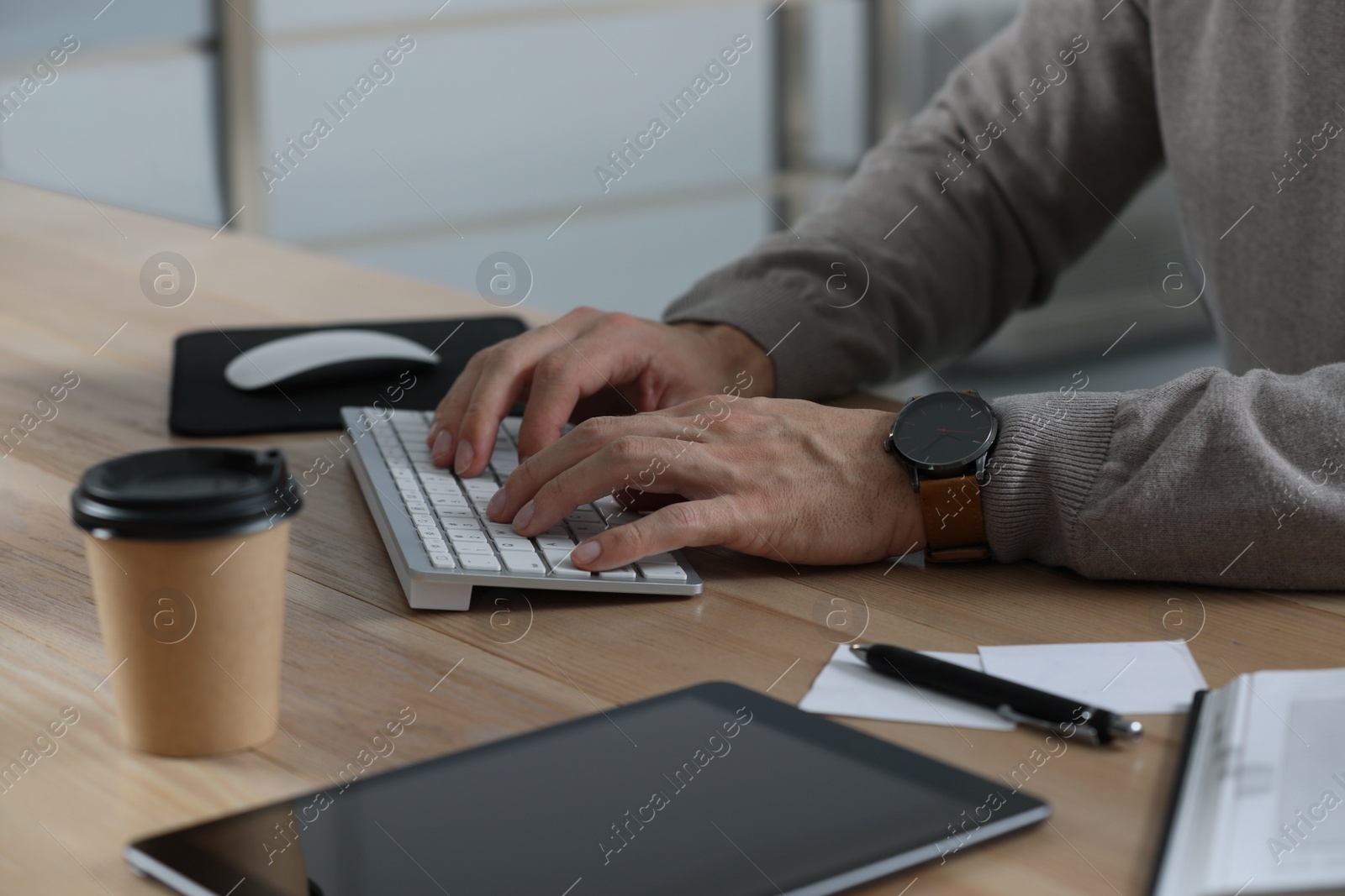 Photo of Man working on computer at table in office, closeup