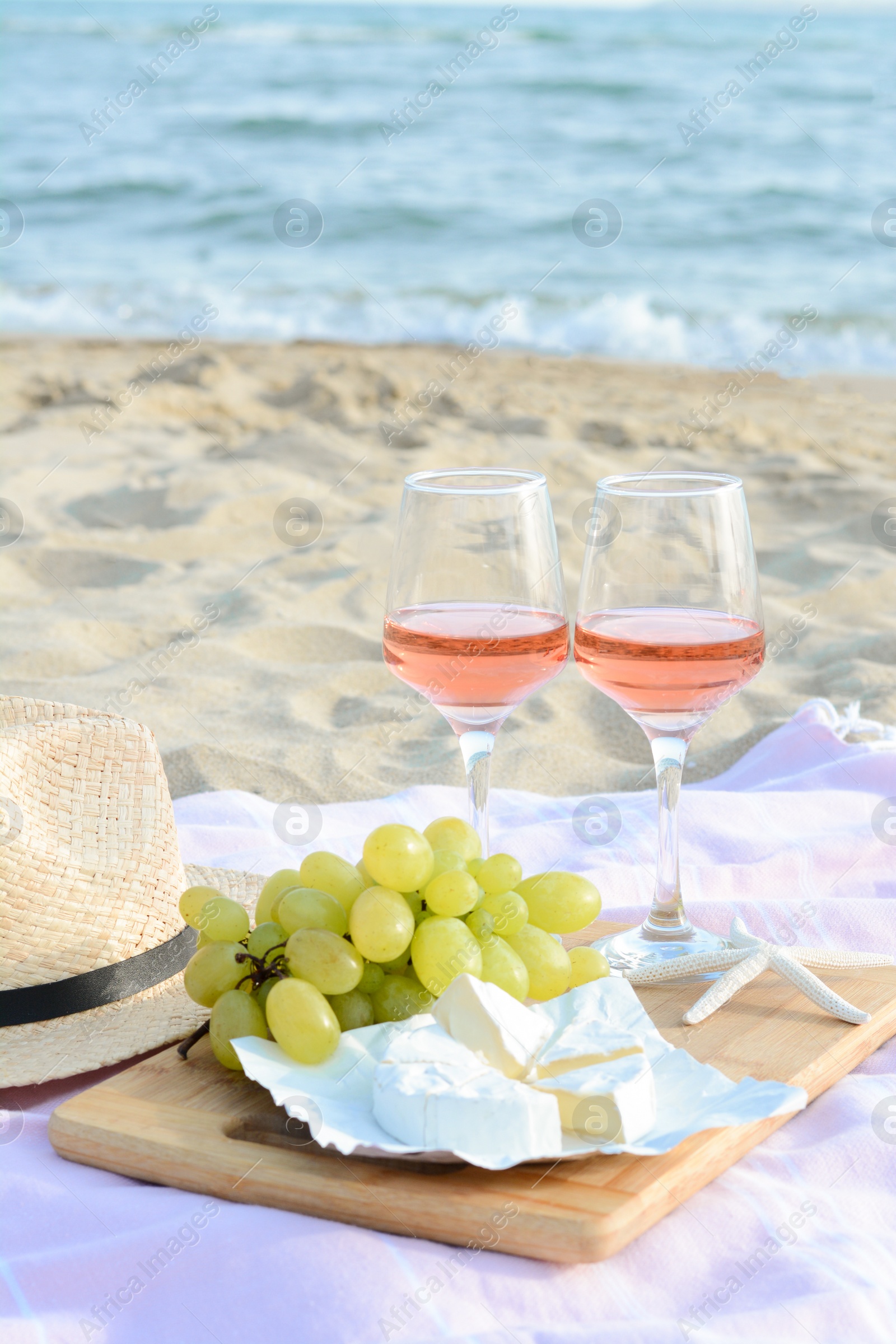 Photo of Glasses with rose wine and snacks for beach picnic on sandy seashore