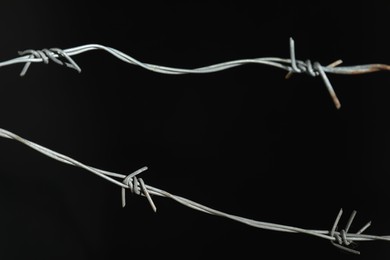 Photo of Shiny metal barbed wire on black background, closeup