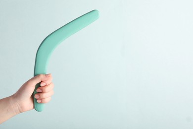 Woman holding boomerang on light background, closeup. Space for text