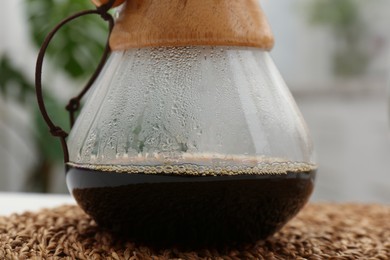 Photo of Glass chemex coffeemaker with coffee on table, closeup