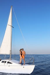 Photo of Young man and his beautiful girlfriend in bikini on yacht. Happy couple during sea trip