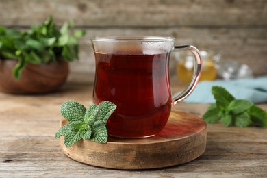 Photo of Cup of hot aromatic tea with mint on wooden table