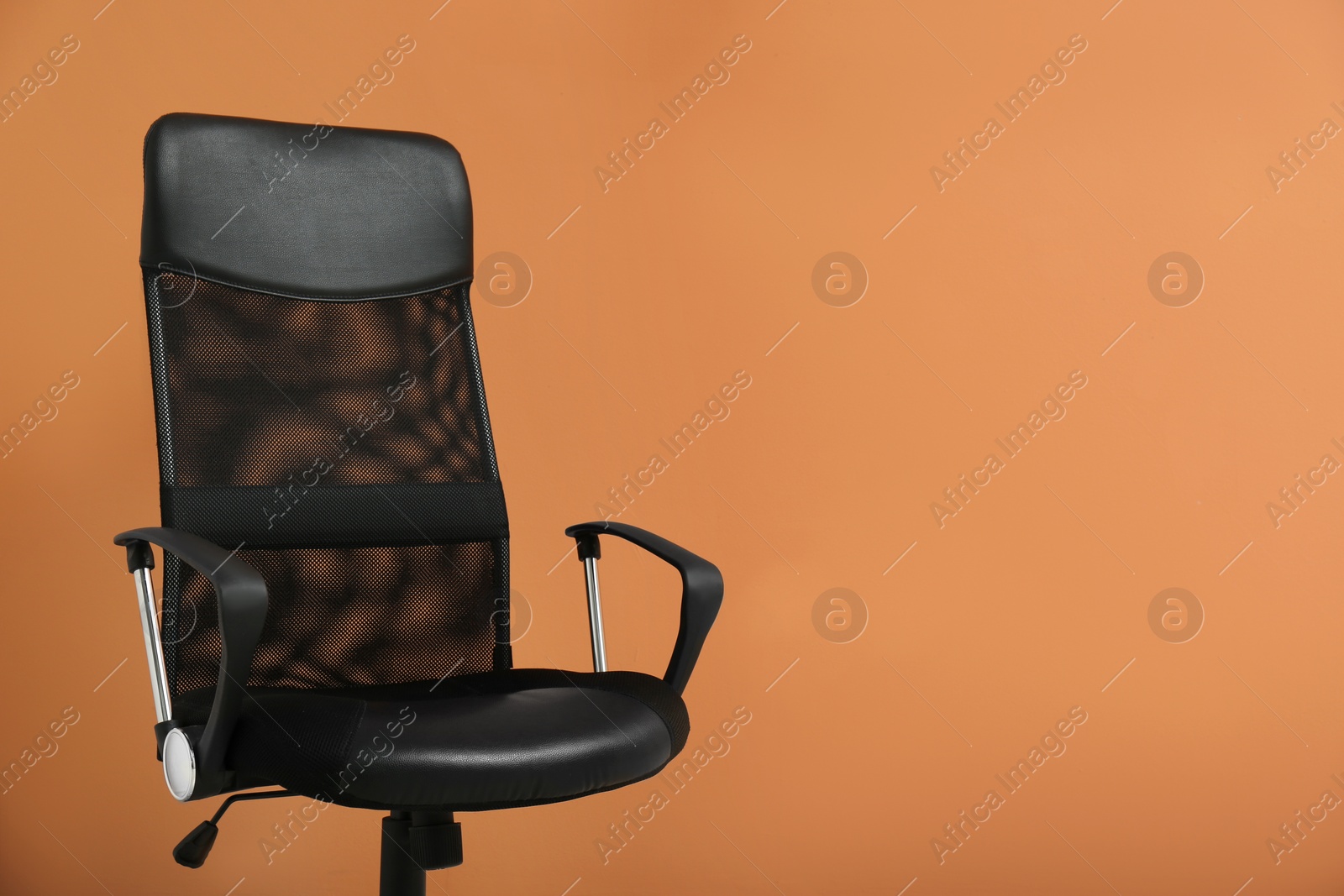 Photo of Modern office chair on orange coral background. Space for text