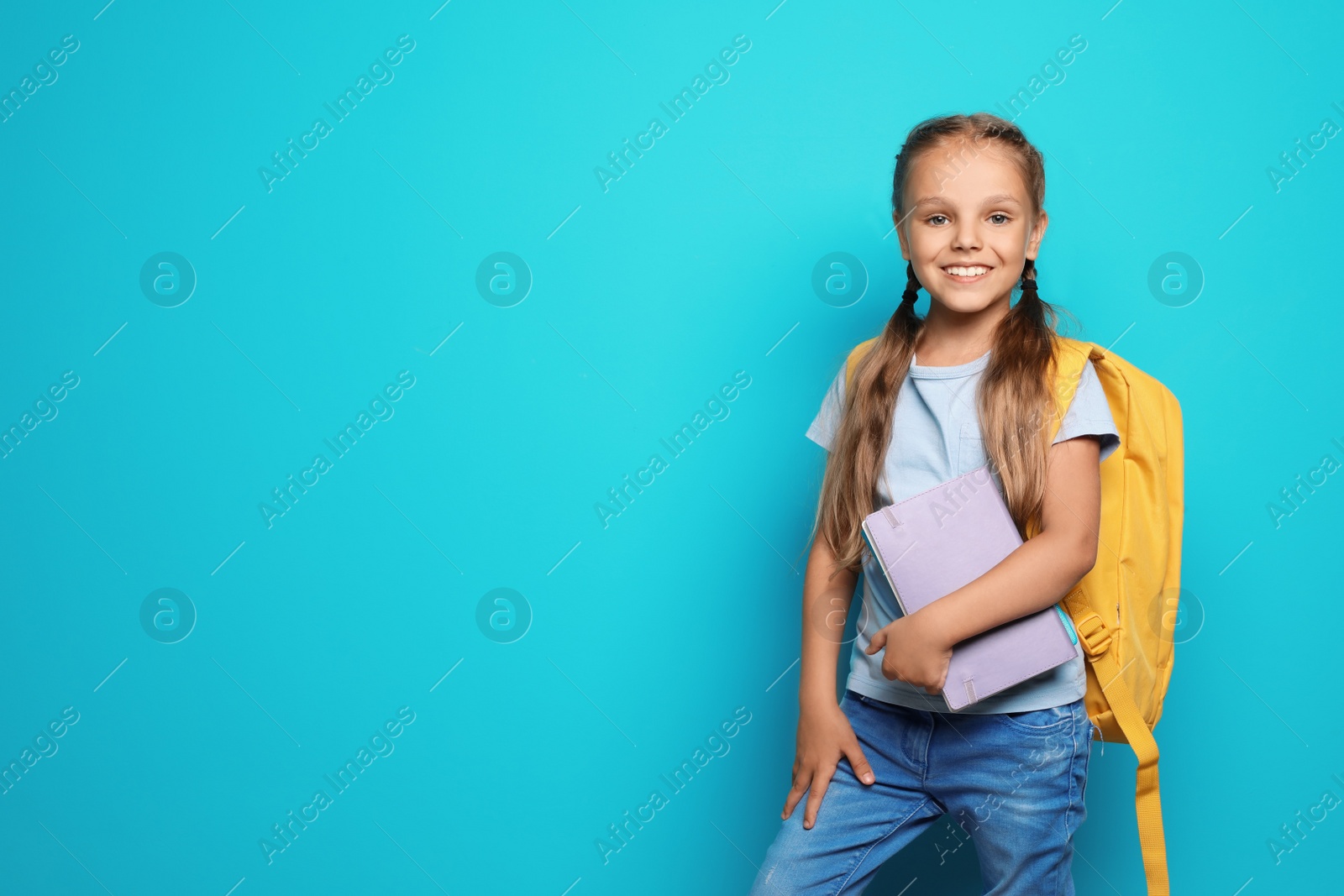 Photo of Little school child with backpack and copybook on color background