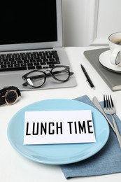 Business lunch. Office desk with plate, cutlery and laptop. Card with phrase Lunch Time on dish