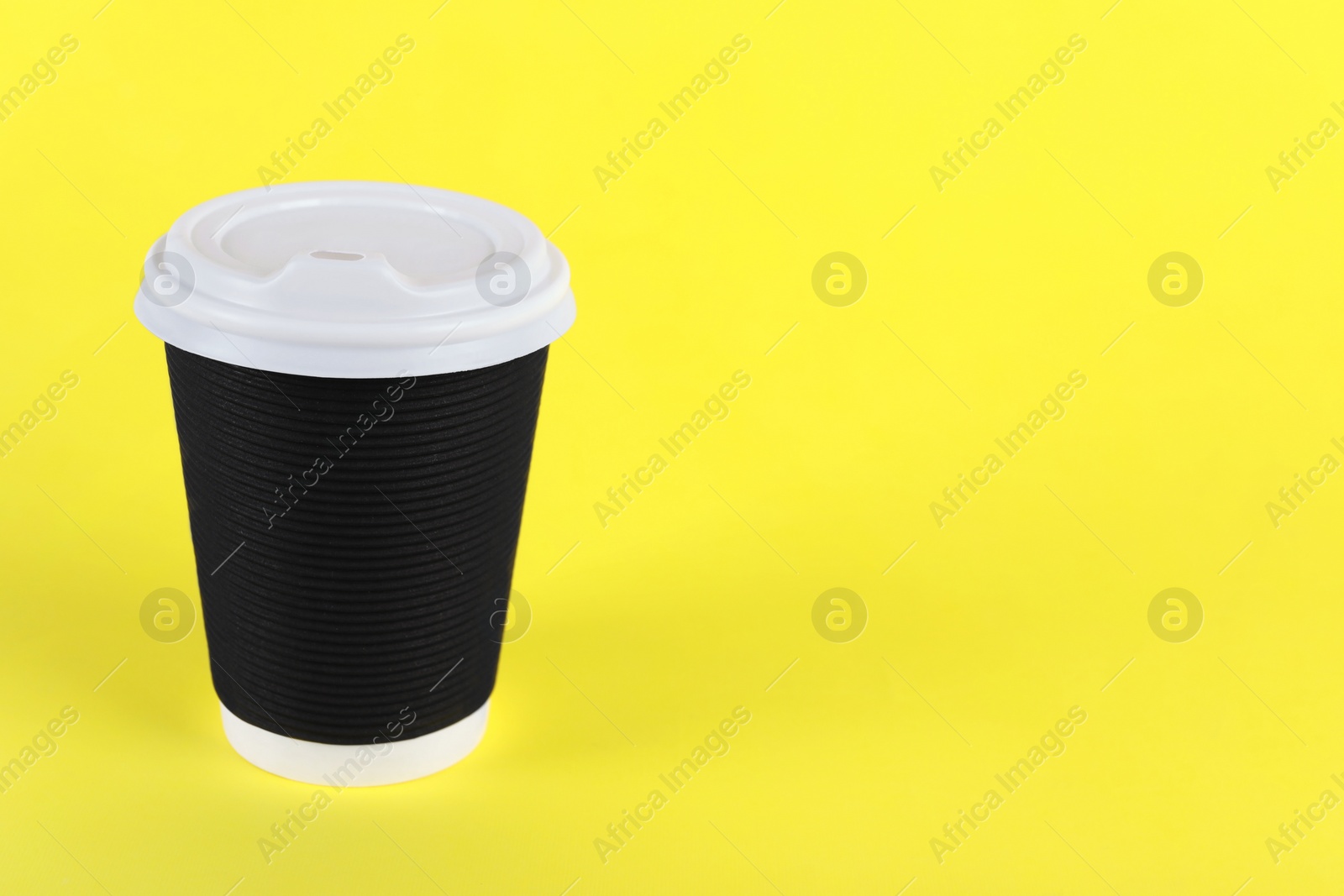 Photo of Black paper cup with plastic lid on yellow background, space for text. Coffee to go