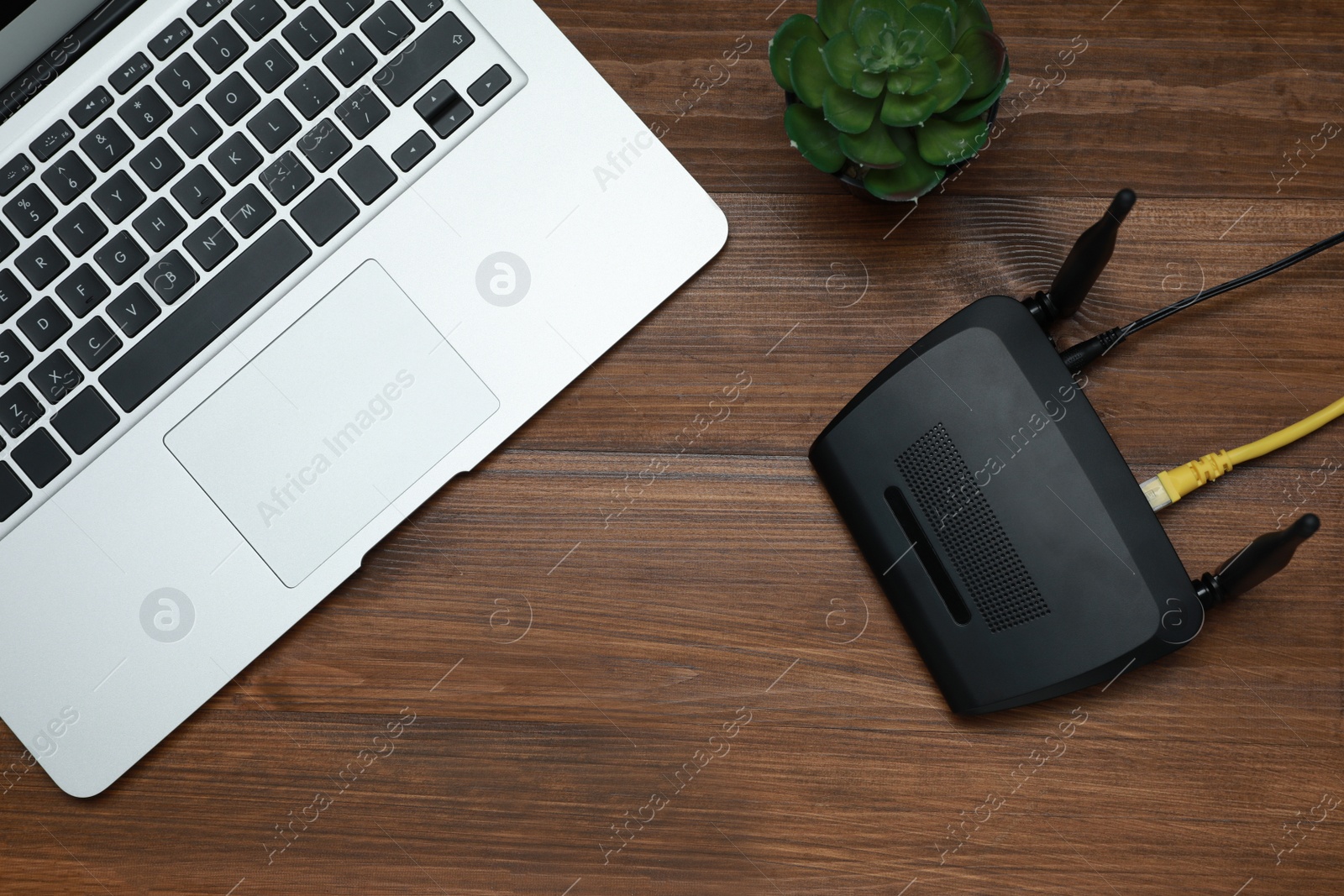 Photo of Modern router and laptop on wooden table, flat lay