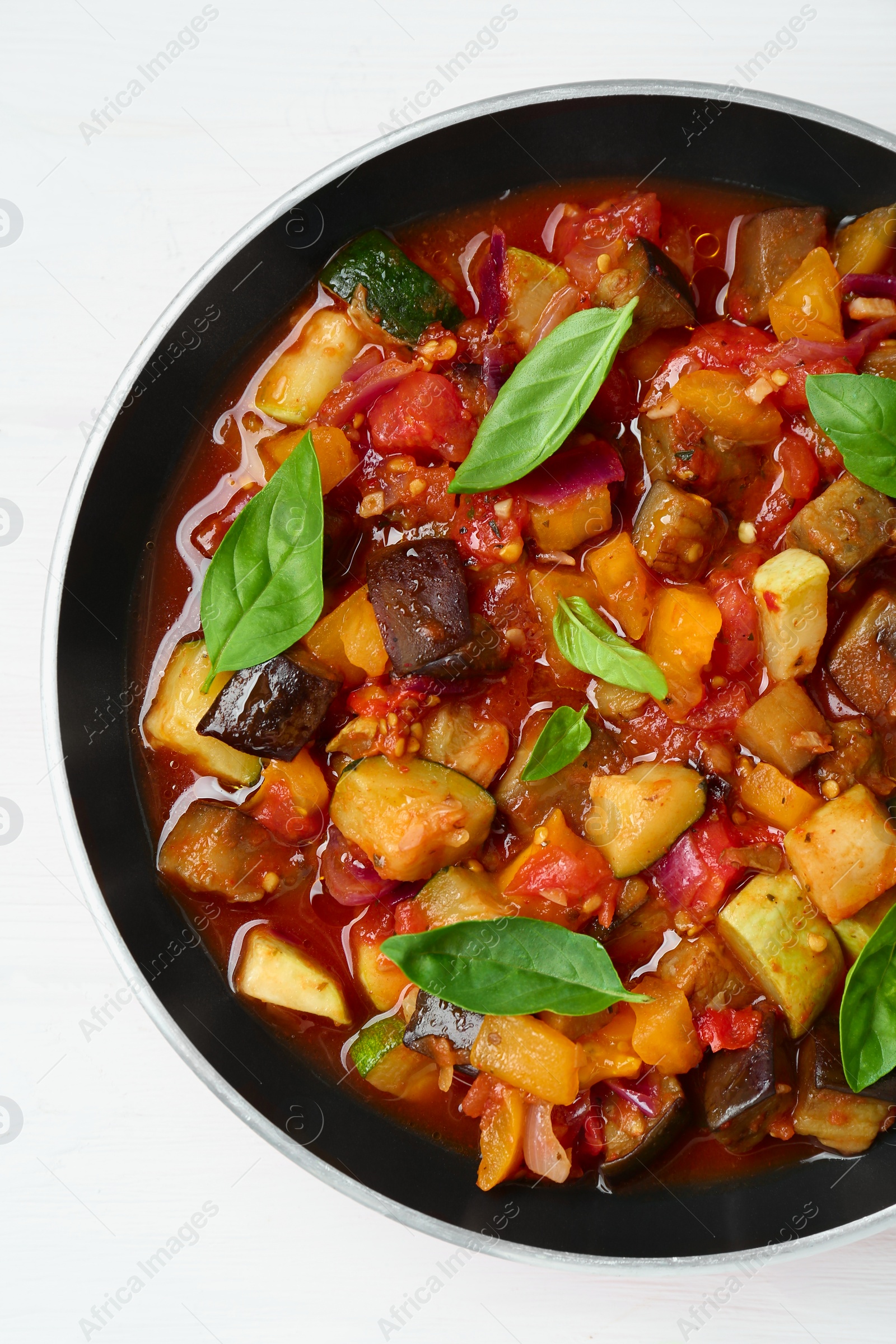 Photo of Frying pan with tasty ratatouille on white wooden table, top view