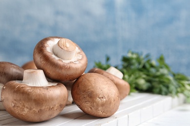 Photo of Fresh champignon mushrooms on wooden board, closeup. Space for text