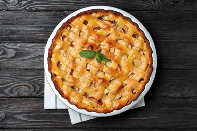 Traditional apple pie with mint on black wooden table, top view