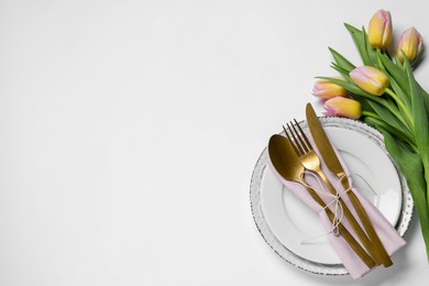 Photo of Stylish table setting with cutlery and tulips on white background, flat lay. Space for text