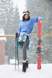 Photo of Young woman with skis wearing winter sport clothes and goggles outdoors