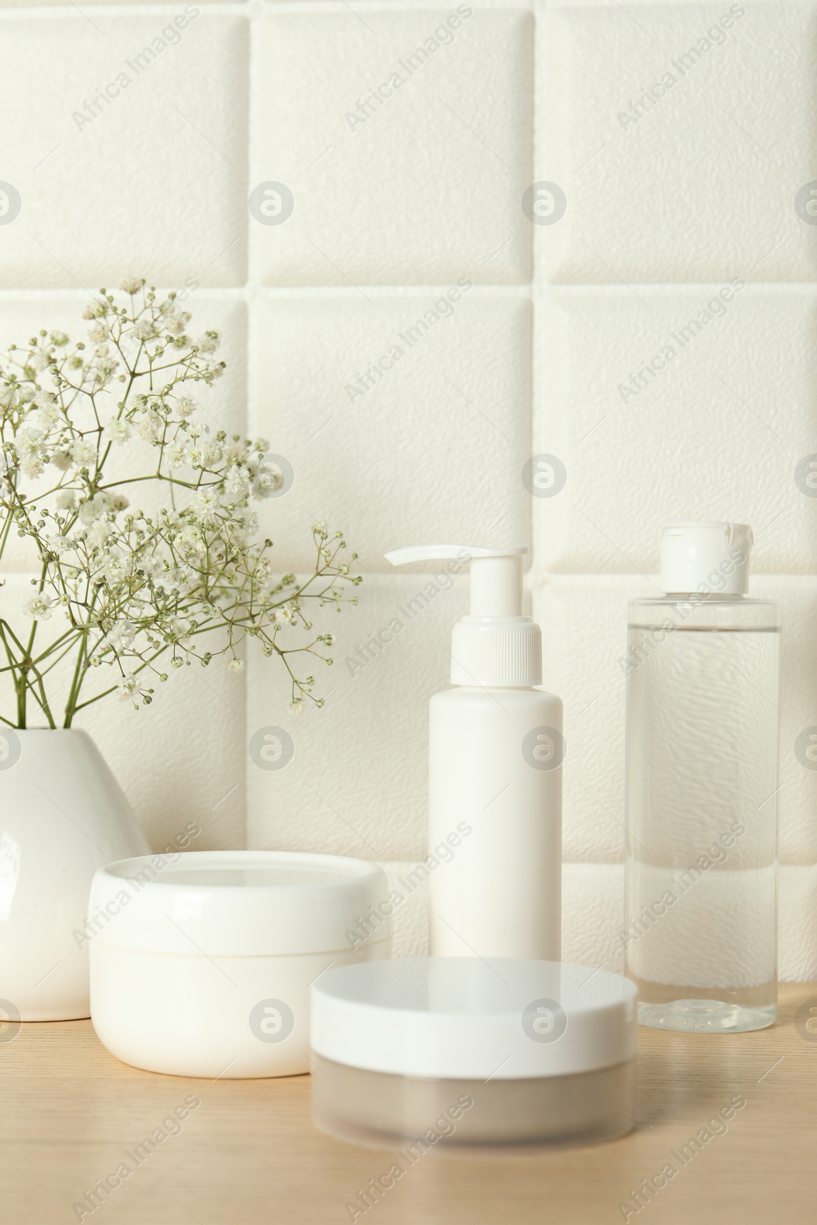 Photo of Bath accessories. Different personal care products and gypsophila flowers in vase on wooden table near white tiled wall