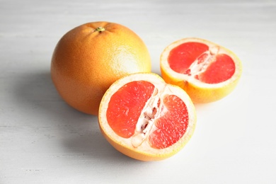 Photo of Whole and sliced tasty grapefruits on wooden table