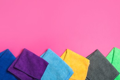 Photo of Many colorful microfiber cloths on pink background, flat lay. Space for text