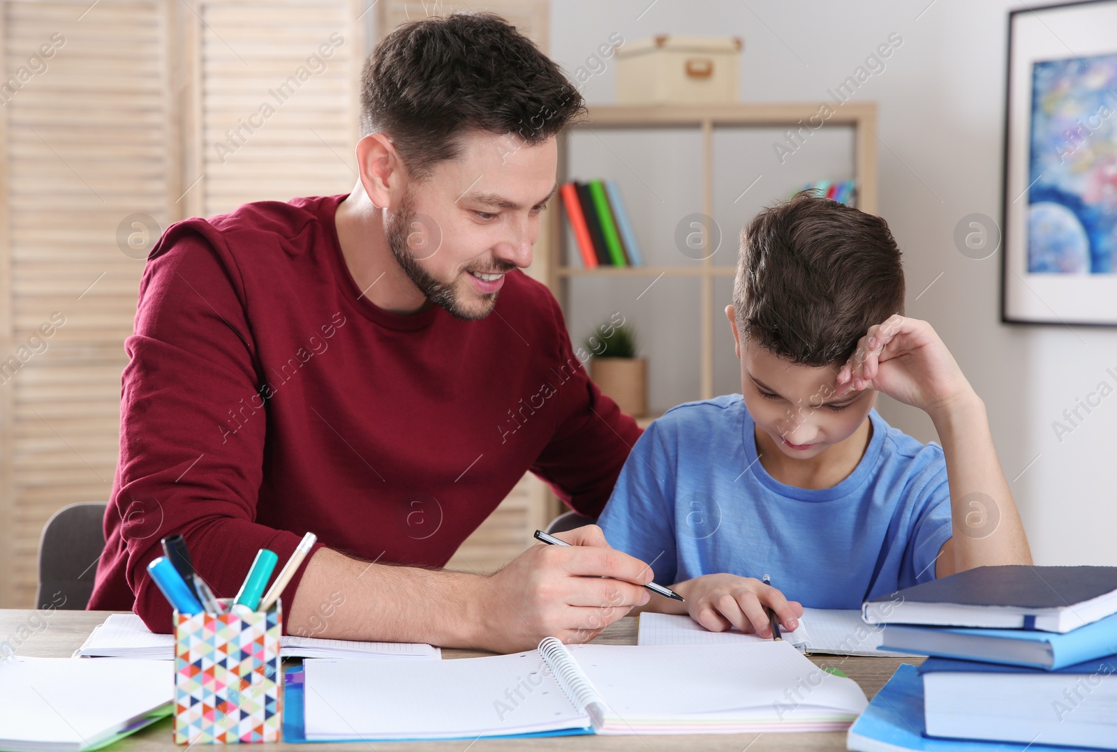 Photo of Dad helping his son with homework in room