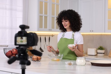 Photo of Smiling food blogger cooking while recording video in kitchen