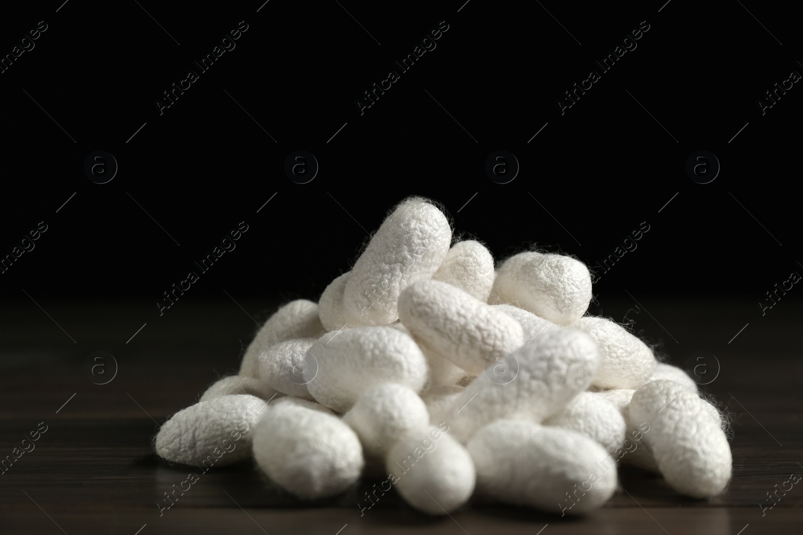 Photo of Heap of white silk cocoons on wooden table, closeup