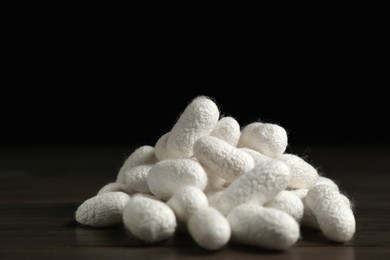 Photo of Heap of white silk cocoons on wooden table, closeup