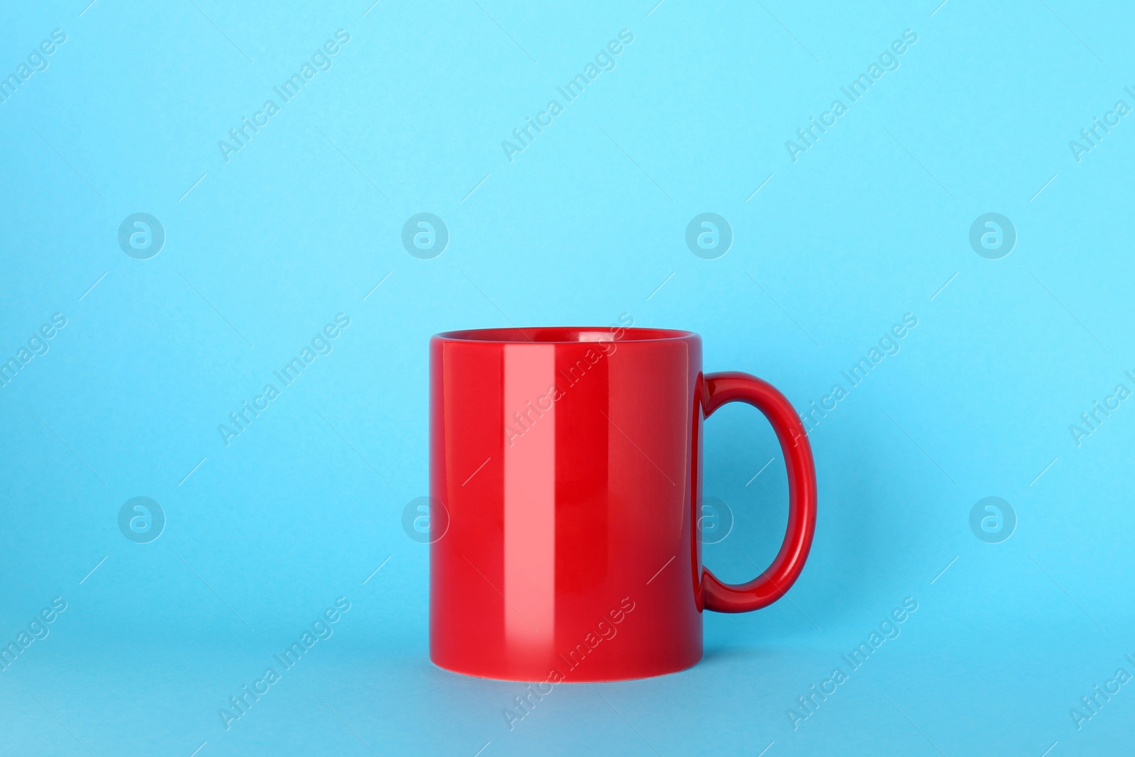 Blank red ceramic mug on light blue background Photo of Blank red ceramic mug on light blue background