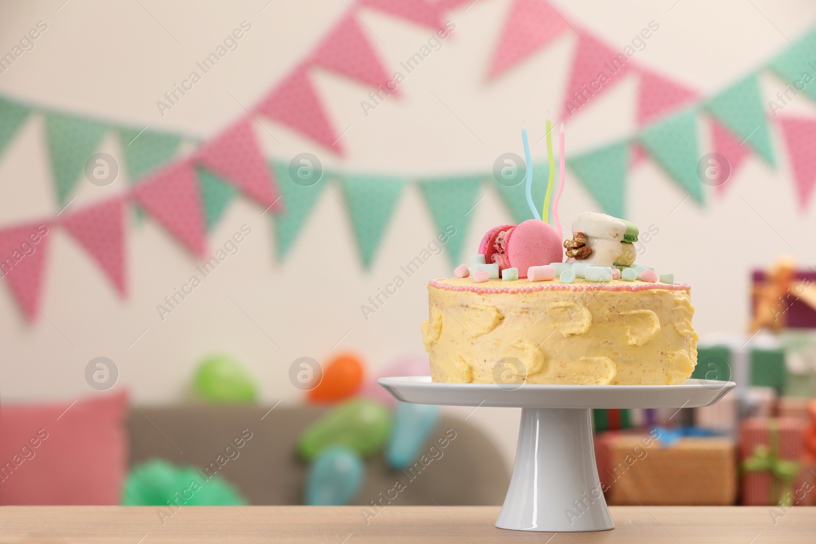 Photo of Delicious cake decorated with macarons and marshmallows on wooden table in festive room, space for text