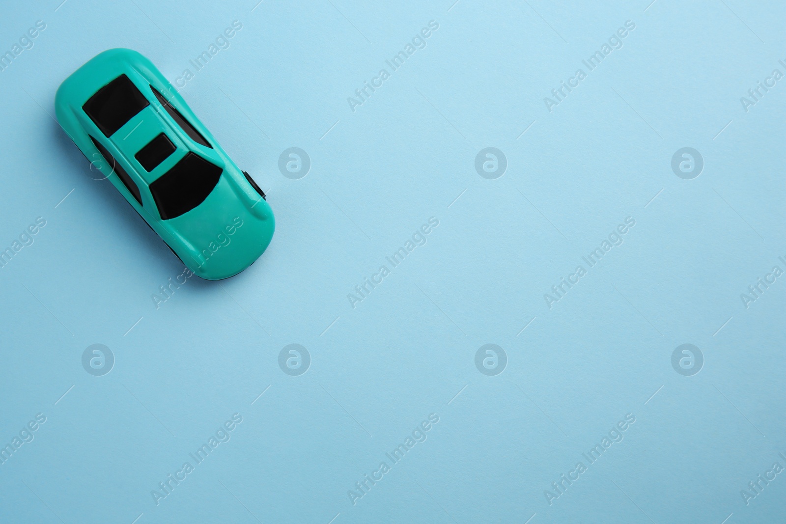 Photo of One bright car on light blue background, top view with space for text. Children`s toy