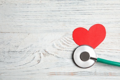Photo of Stethoscope and red heart on wooden background, top view with space for text. Cardiology concept