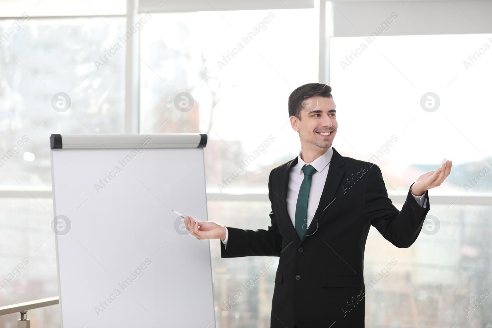 Photo of Business trainer giving presentation on flip chart board indoors