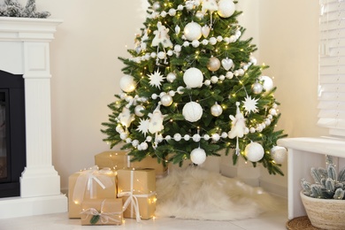 Decorated Christmas tree with faux fur skirt and gift boxes indoors