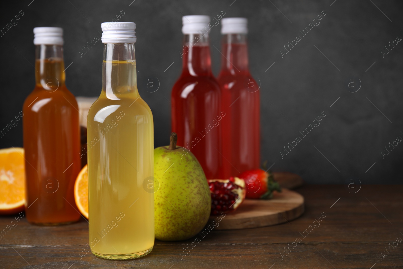 Photo of Delicious kombucha in glass bottles and fresh fruits on wooden table, space for text