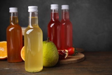 Photo of Delicious kombucha in glass bottles and fresh fruits on wooden table, space for text