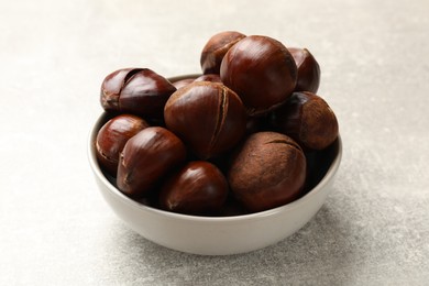 Fresh edible sweet chestnuts in bowl on grey table