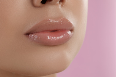 Photo of Young woman with beautiful full lips on pink background, closeup